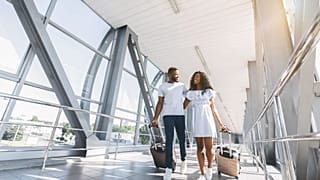 Un couple d'Afro-Américains se promène dans un aéroport avec des valises.