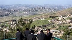 يهود متشددون من كيبوتس مسغاف عام بشمال إسرائيل ينظرون إلى قرية العديسة بجنوب لبنان بعد انسحاب إسرائيل جزئيا من القرى الحدودية، 18 فبراير/شباط 2025