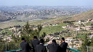 يهود متشددون من كيبوتس مسغاف عام بشمال إسرائيل ينظرون إلى قرية العديسة بجنوب لبنان بعد انسحاب إسرائيل جزئيا من القرى الحدودية، 18 فبراير/شباط 2025