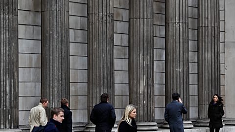 File photo of people walking outside the Bank of England, in London's City financial district, Tuesday, Feb. 14, 2012. 