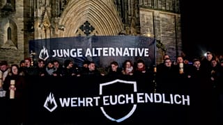 FILE: People carry banners reading "young alternative, defend yourself" attending an AfD election campaign in front of the cathedral in Magdeburg, 23 December 2024