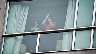 تعدادی از مهاجران دیپورت شده از آمریکا در زور چهارشنبه ۱۹ فوریه از پشت پنجره هتل پاناماسیتی برای خبرنگاران دست تکان می‌دهند