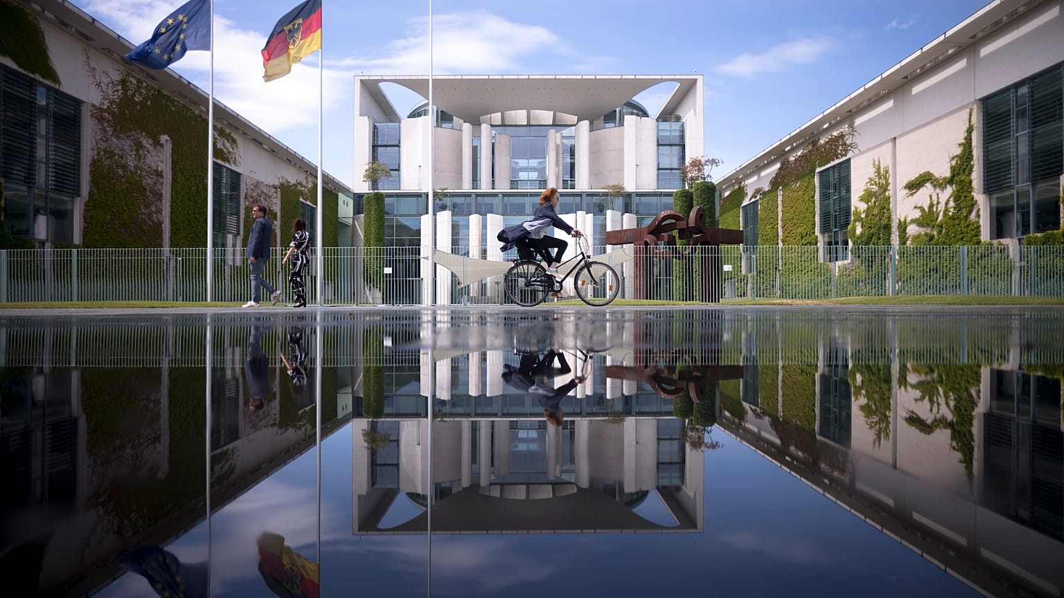Berlin'de güneşli bir günde bir fıskiyenin oluşturduğu su birikintisine yansıyan Alman şansölyelerinin ofisinin bulunduğu Başbakanlık binasının dosya fotoğrafı