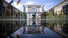 Berlin'de güneşli bir günde bir fıskiyenin oluşturduğu su birikintisine yansıyan Alman şansölyelerinin ofisinin bulunduğu Başbakanlık binasının dosya fotoğrafı