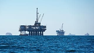 Kargo gemileri, Kaliforniya kıyılarındaki petrol platformlarıyla aynı alanı paylaşarak açıkta demirlemiş halde görülüyor. 
