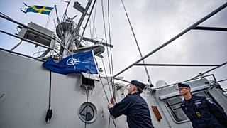 Kaptan Thomas Zimmerman, sağda, İsveç'in Karlskrona kentindeki donanma limanından yola çıkan devriye gemisi HMS Carlskrona'ya (P04) NATO bayrağını çekme emrini veriyor.
