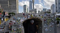 Un visiteur traverse une réplique d'un tunnel de la bande de Gaza, sur la place où se rassemblement les familles des otages à Tel Aviv, en Israël.
