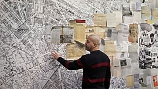 French street artist Shuck One tears up archive images as he prepares a mural for the exhibition "Paris Noir"
