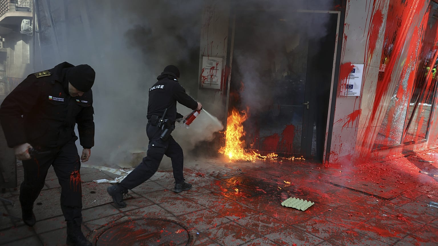 A polícia combate um incêndio ateado por manifestantes nacionalistas à porta do gabinete da Comissão Europeia em Sófia, 22 de fevereiro de 2025