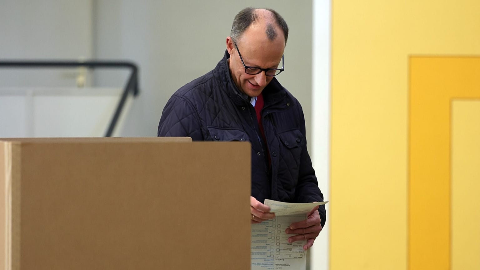 Friedrich Merz, líder da União Democrata-Cristã (CDU), dirige-se a uma cabina de voto com o seu boletim de voto numa assembleia de voto em Arnsberg-Niedereimer, 23 de fevereiro de 2025