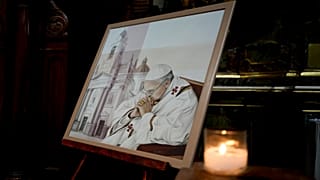 Eine Kerze leuchtet neben einem Bild von Papst Franziskus in der Basilika San José de Flores in Buenos Aires, Argentinien, wo er als Jugendlicher Gottesdienst feierte, Sonntag, 23. Februar 2025. 