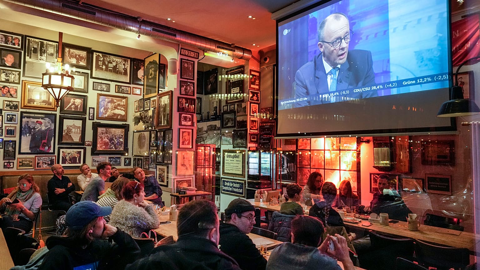 Des personnes regardent une discussion télévisée avec Friedrich Merz, leader de CDU, dans un pub à Berlin, le 23 février 2025, après les élections nationales allemandes. 