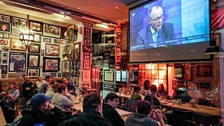 Des personnes regardent une discussion télévisée avec Friedrich Merz, leader de CDU, dans un pub à Berlin, le 23 février 2025, après les élections nationales allemandes.