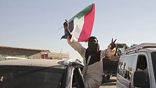ملف: رجل سوداني يلوح بعلم السودان في مروي، السودان، السبت، 11 يناير/كانون الثاني 2025.