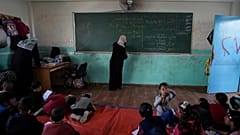 Un profesor con niños en una clase improvisada en Deir al-Balah, recientemente invadida por tierra, el domingo 21 de abril de 2024.