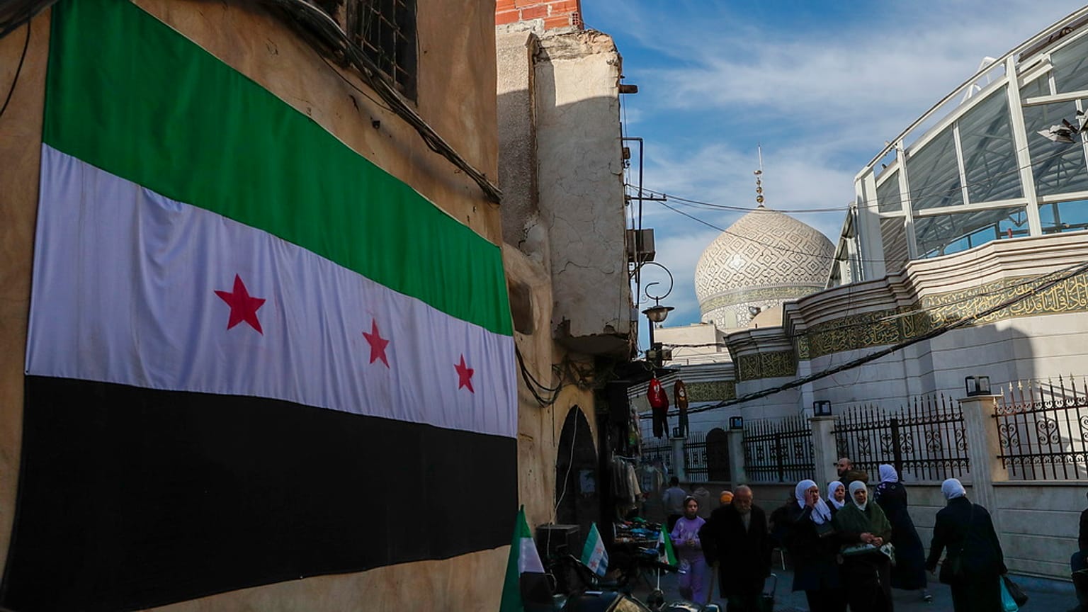 علم "الثورة السورية" يرفرف في المدينة القديمة بدمشق، سوريا، يوم الخميس، 9 كانون الثاني/يناير 2025.
