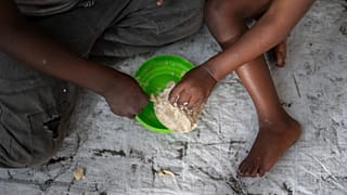 Mulheres e crianças comem numa escola da RDC em fevereiro de 2025.