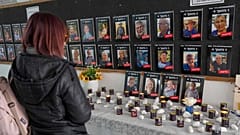 Una mujer mira las fotos de los rehenes asesinados (fila inferior, de izquierda a derecha) Ariel Bibas, su madre Shiri, su hermano Kfir y Oded Lifshitz, a la derecha.