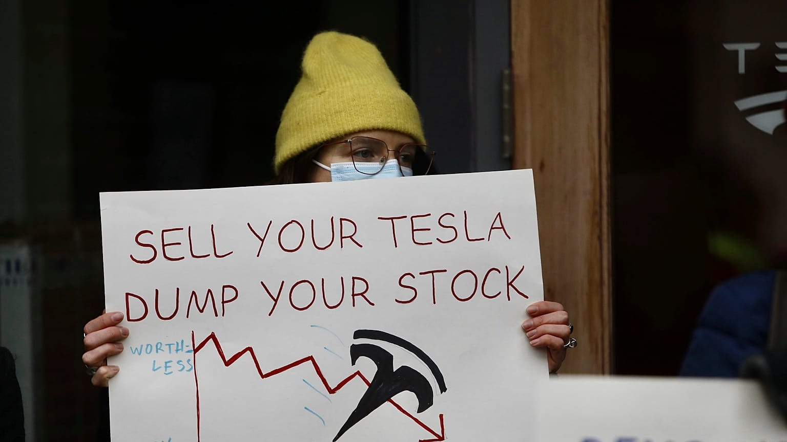 Um manifestante segura um cartaz à porta de um salão de exposição da Tesla em Seattle 