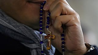 Ein Mann nimmt an einem Rosenkranzgebet mit Kardinal Luis Antonio Tagle für die Gesundheit von Papst Franziskus auf dem Petersplatz im Vatikan teil, Dienstag, 25. Februar 2025. 
