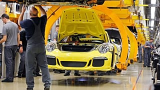 An employee works at a Porsche 911during a press tour at the Porsche manufacturing plant in Stuttgart, Germany, Tuesday, March 10, 2015. 