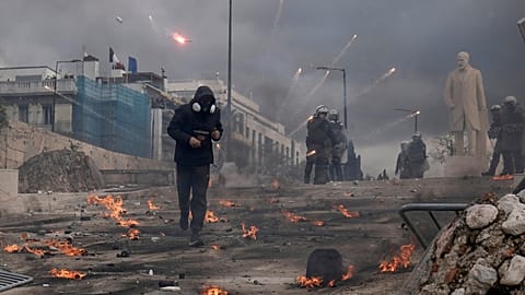 A protester runs past riot police outside Parliament in Athens during a rally marking two years since the rail disaster, Greece, 28.02.2025