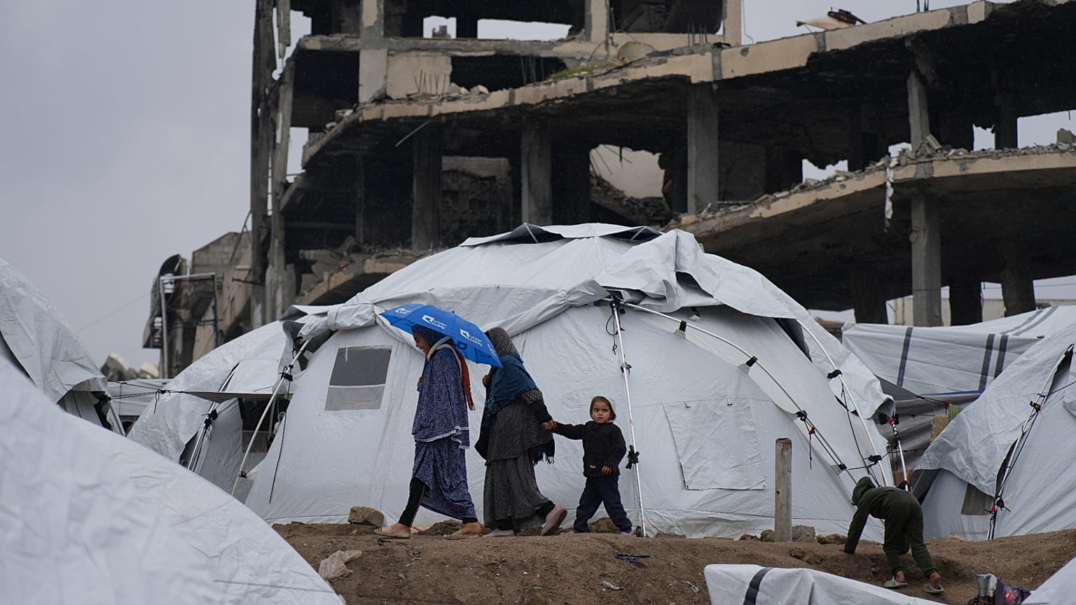 عائلة فلسطينية تمشي بين الخيام في مدينة غزة، قطاع غزة، السبت، 1 مارس/آذار 2025