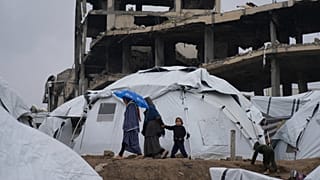 عائلة فلسطينية تمشي بين الخيام في مدينة غزة، قطاع غزة، السبت، 1 مارس/آذار 2025