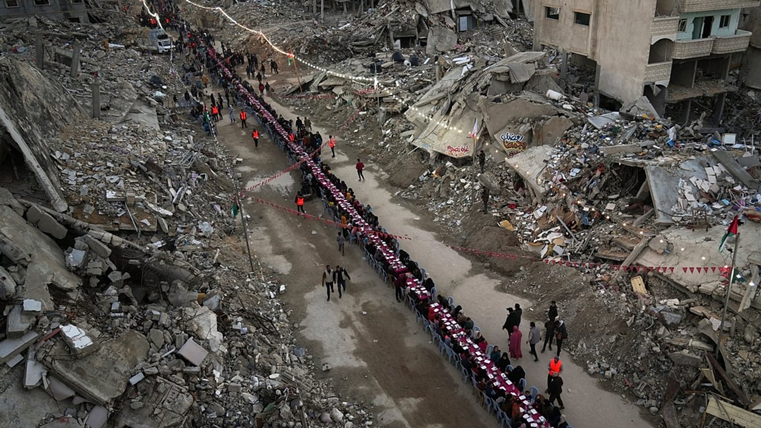 فلسطينيون يجتمعون حول طاولة محاطة بأنقاض المنازل المدمرة لتناول وجبة الإفطار، في أول أيام شهر رمضان، في رفح جنوب قطاع غزة، في 1 مارس 2025.