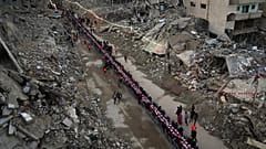 فلسطينيون يجتمعون حول طاولة محاطة بأنقاض المنازل المدمرة لتناول وجبة الإفطار، في أول أيام شهر رمضان، في رفح جنوب قطاع غزة، في 1 مارس 2025.