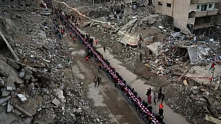 فلسطينيون يجتمعون حول طاولة محاطة بأنقاض المنازل المدمرة لتناول وجبة الإفطار، في أول أيام شهر رمضان، في رفح جنوب قطاع غزة، في 1 مارس 2025.