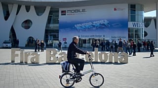 Un uomo va in bicicletta fuori dal Mobile World Congress, la più grande fiera di telefonia mobile del mondo, a Barcellona, Spagna, domenica 23 febbraio 2014.