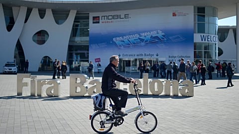 A man rides his bicycle outside the Mobile World Congress, the world's largest mobile phone trade show in Barcelona, Spain, Sunday, Feb. 23, 2014.