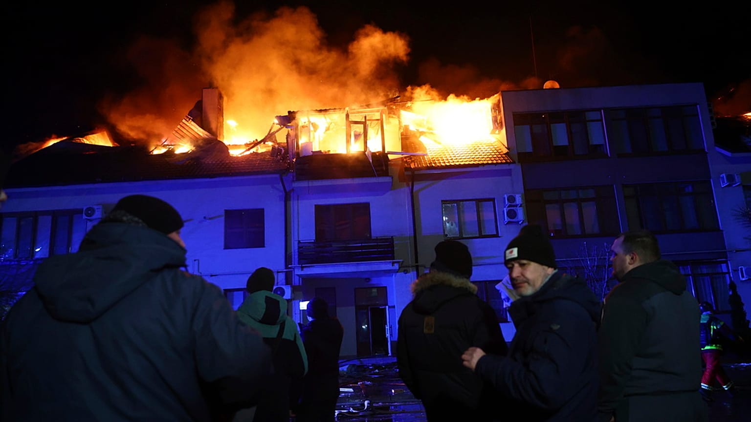 Κάτοικοι στέκονται μπροστά από φλεγόμενο σπίτι που χτυπήθηκε από ρωσικό μη επανδρωμένο αεροσκάφος σε κατοικημένη γειτονιά στη Ζαπορίζια της Ουκρανίας, Σάββατο 1 Μαρτίου 2025.