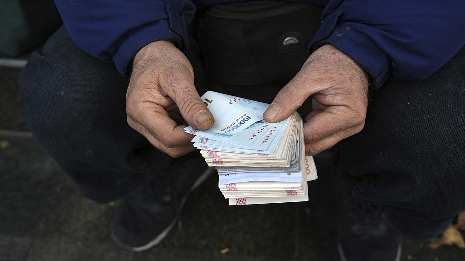 Tahran şehir merkezindeki bir ticaret bölgesinde bir sokak sarrafı İran banknotlarını sayıyor, 23 Aralık, 2022