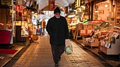 A man carries a bag with groceries in a food street market at Uskudar neighbourhood in Istanbul, Turkey, Thursday, Jan. 23, 2025.
