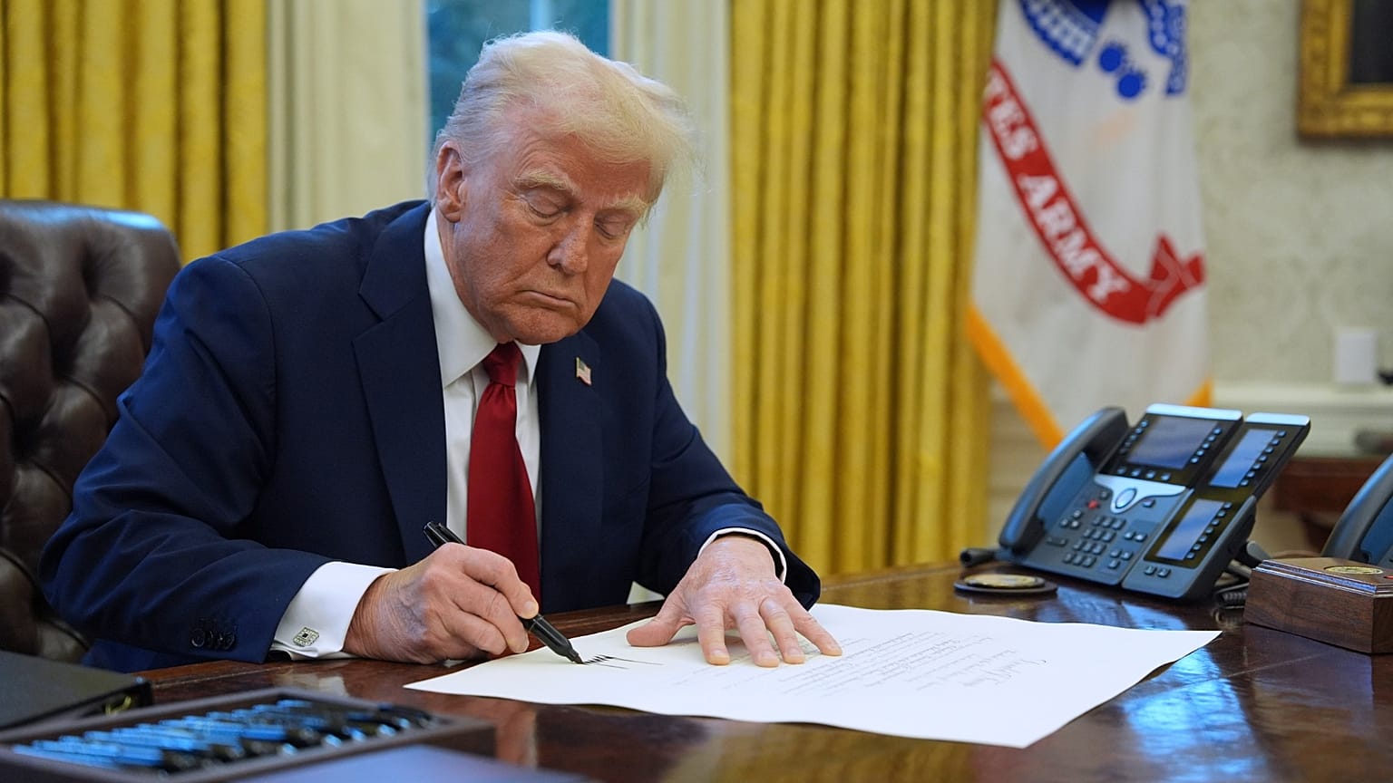 FILE - President Donald Trump signs a document in the Oval Office at the White House, 30 January 2025