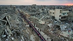 Napnyugta után a romok között terített asztalhoz ülnek palesztinok Rafahban 