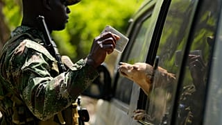 ARCHIVO: Un paramilitar comprueba la identificación de un viajero en la región del Cañón de Micay, suroeste de Colombia, 24 de agosto de 2024.