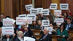 Muhalefet milletvekilleri "Genel grev!" yazılı pankartlar taşıyor: "Genel grev!" 4 Mart 2025, Salı günü Sırbistan'ın başkenti Belgrad'da düzenlenen parlamento oturumu sırasında.