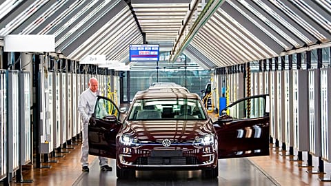 In this March 5, 2018 file photo, Roland Schulz makes the final check of an e-Golf electric car in the German car manufacturer Volkswagen's factory in Germany. 