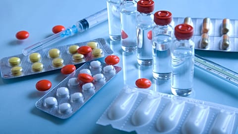 A collection of pills and syringes on a blue background. 