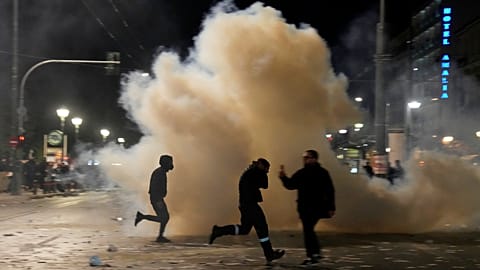 Des gens courent pour éviter les gaz lacrymogènes lors d'affrontements avec la police anti-émeute à Athènes, mercredi 5 mars 2025.