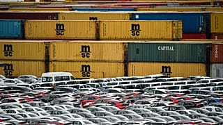 Coches de exportación e importación se almacenan delante de contenedores el jueves 16 de mayo de 2019 en el puerto de Bremerhaven, Alemania