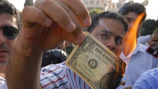 صورة من الأرشيف- متظاهر مؤيد للرئيس السوري بشار الأسد، يحرق ورقة نقدية بالدولار الأمريكي في دمشق، سوريا، يوم الجمعة 8 يوليو 2011