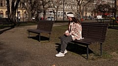 Egy kárpátaljai menekült, Kenéz Andrea nézi a telefonját egy budapesti parkban