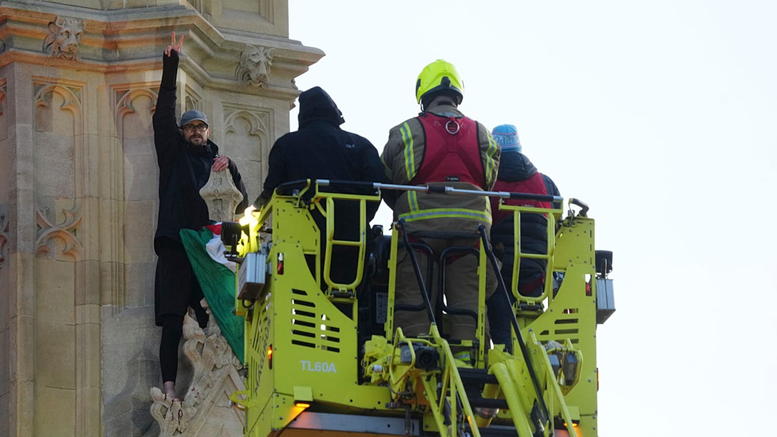 Emergency services talk to a man with a Palestinian flag after he climbed up Elizabeth Tower, March 8th 2025