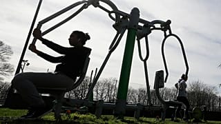 Des personnes utilisent des équipements de gymnastique en plein air dans un parc au Royaume-Uni en mars 2020.