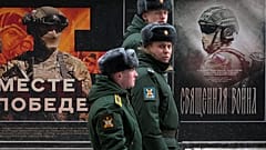 Bir askeri devriye, 24 Şubat 2025 tarihinde Rusya'nın St Petersburg kentinde Rus ordusuna adanmış 'Birlikte Zafere' adlı askeri posterlerden oluşan bir sokak sergisinin önünden geçiyor.