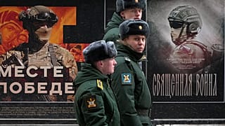 Bir askeri devriye, 24 Şubat 2025 tarihinde Rusya'nın St Petersburg kentinde Rus ordusuna adanmış 'Birlikte Zafere' adlı askeri posterlerden oluşan bir sokak sergisinin önünden geçiyor.